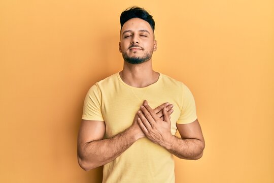 Young arab man wearing casual clothes smiling with hands on chest with closed eyes and grateful gesture on face. health concept.
