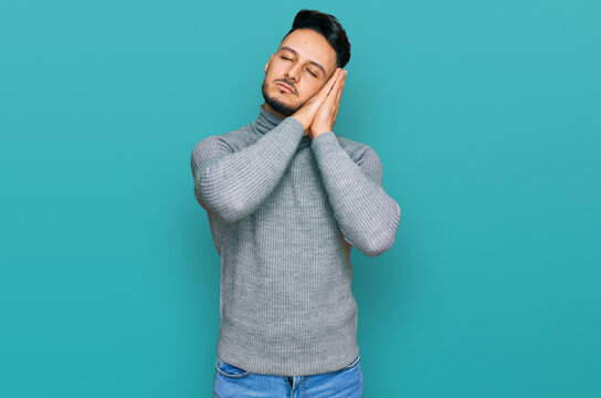 Young arab man wearing casual clothes sleeping tired dreaming and posing with hands together while smiling with closed eyes.