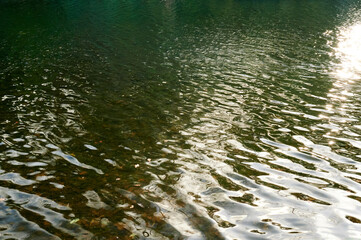 ripples on water on lake with green yellow reflection in winter