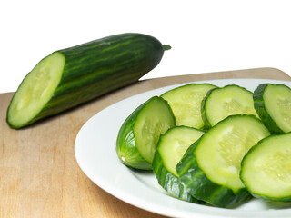  A smooth, medium-sized cucumber cut into slices. Cucumber on a cutting board. Vegetable isolate. Fresh ripe vegetable