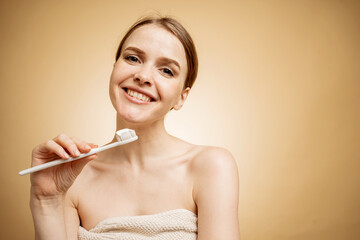 A woman uses a toothbrush and toothpaste, shows her teeth and smiles