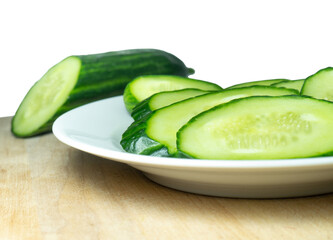  A smooth, medium-sized cucumber cut into slices. Cucumber on a plate. Vegetable isolate. Fresh ripe vegetable