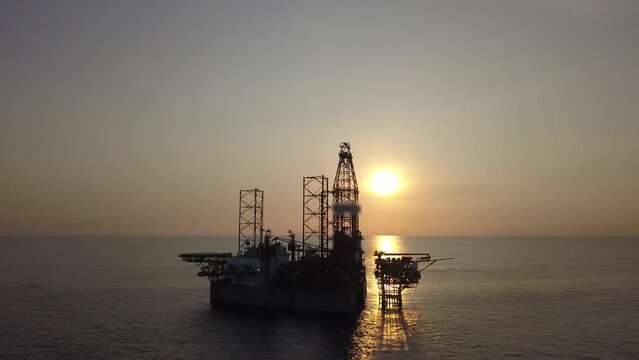 Aerial view from a drone of an offshore jack up rig at the offshore location during sunrise time
