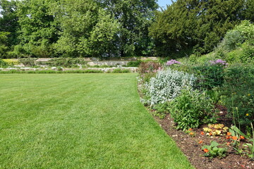 Beautiful Verdant Garden with a Freshly Mowed Grass Lawn, Colourful Flower Bed and Green Leafy Trees