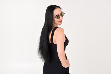 Portrait of a beautiful brunette woman in a black dress with a smile on a white background in a studio with full-length sunglasses	
