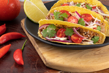 Delicious mexican food tacos stuffed with minced beef, coriander, tomato, cheese, pepper and lemon. Selective focus.