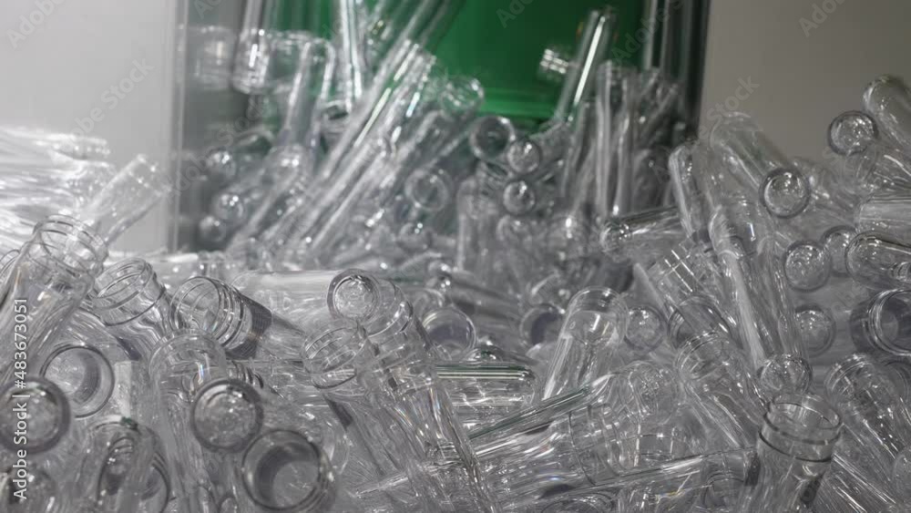 Poster a close-up shot of transparent pet preforms piled up in a container