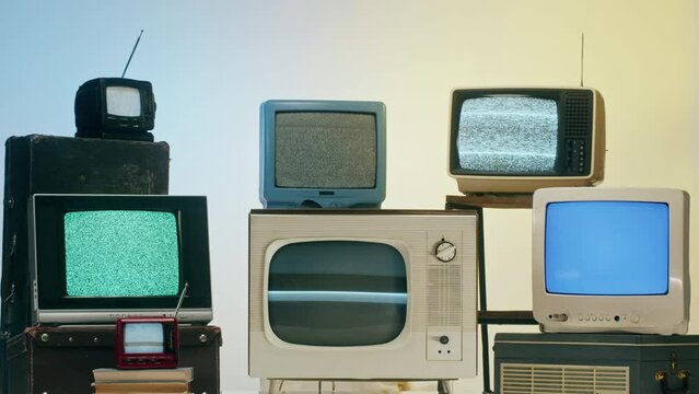 Old televisions with grey interference screen on blue and yellow background. Vintage tv composition, nostalgia. Gray noise screen and glitches.