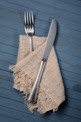 steel fork and knife with napkin on blue table