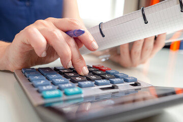 Accounting. Concept of calculating company taxes. Calculator in front of woman accountant. Hands of financial auditor close-up. Woman's hand on keys of calculator. Business finance accounting