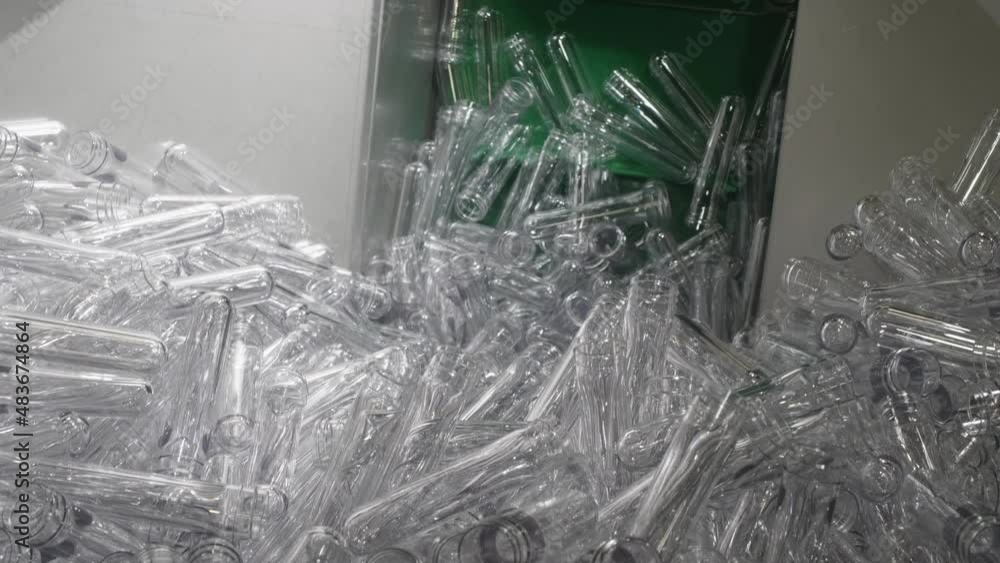 Poster transparent pet preforms are piled up in a container and then the elevator takes them up to the next