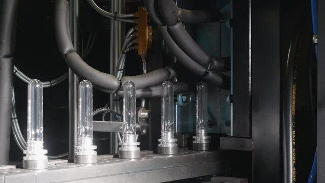 A close-up shot of how PET preforms are moving into a moulding machine, where they are blown into a plastic bottle