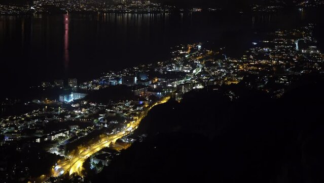 Night view of road E39 leading out from Bergen at night - Cars driving among buildings with light and occasional fireworks around - Static high altitude aerial in sandviken and old Bergen