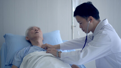 Fototapeta na wymiar Asian doctor checking heart and pulse on senior in hospital bed with stethoscope