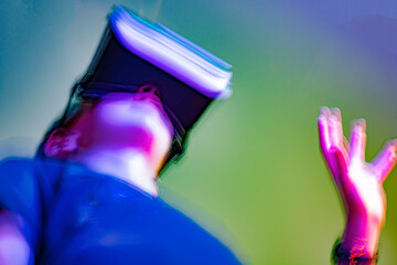 Defocused guy watching video in virtual reality glasses, immersion in a fantasy world. Colorful...