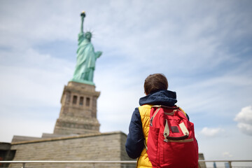 Tourist is traveling to island of liberty. Woman with backpack is on the background of the statue...