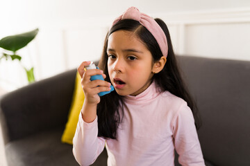 Latin child using an asthma inhaler - obrazy, fototapety, plakaty