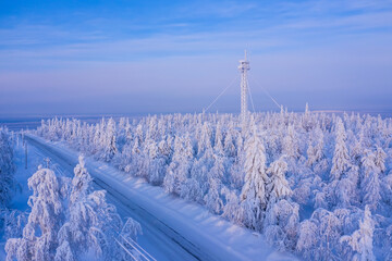 winter road in a snowy forest with a cell tower