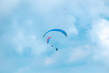 Belmira, Antioquia, Colombia - November 20 2021: Blue and Pink Paragliders, Flying on a Blue Background full of Clouds