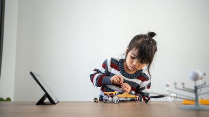 Asian girls enjoy making and fixing electrical robot car and learning online tutor training course