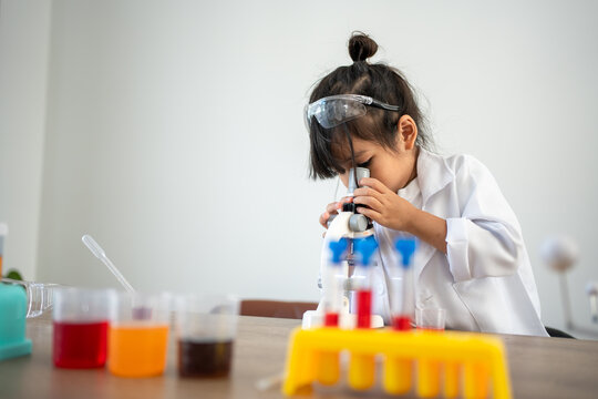 Asian Children In Lab Coat Using A Microscope For A Science Experiment In Homeschool Laboratory