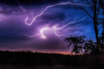 A linear lightning in a purple sky at the night - Powered by Adobe