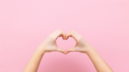 Fototapeta premium Banner young woman holding hands in shape of heart on pink background.