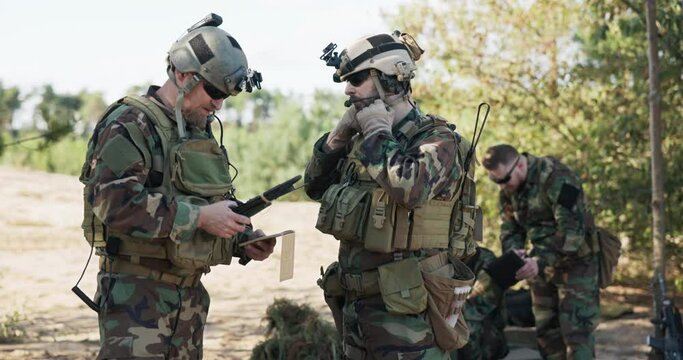 Soldiers belonging to powerful army are preparing strategy for battle surprise enemy enter data into system talk prepare equipment dressed in uniforms camouflage helmets training ground