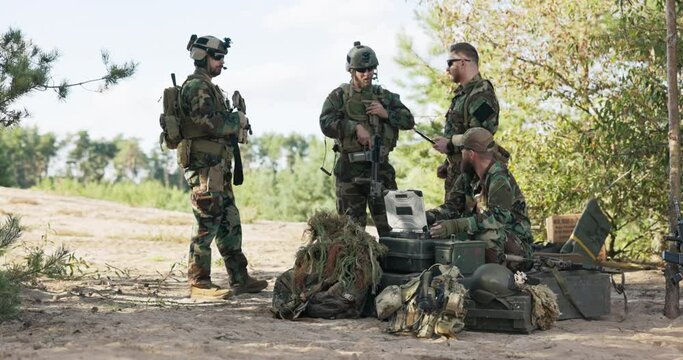 Group of servicemen set up details of today's action defending territory prepare equipment clothes for expedition in forest soldiers follow maps enter data on computer send information to base