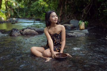 Fototapeta premium Beautiful young Asian girl rests and bathes in the river