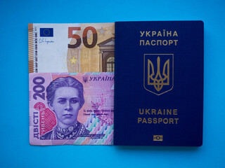 A set of European Union and Ukraine money with a face value of 50 euros and 200 hryvnia on blue. Background of the fifty euros, two hundred hryvnia banknotes and Ukraine passport with copy space. 