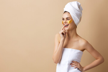 woman golden patches on the face with a towel on the head beige background