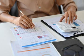 Fototapeta premium Close up with female accountant using calculator to calculate the numbers, finance accounting concept.