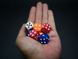 A hand holds a mixed color of dice. Black background