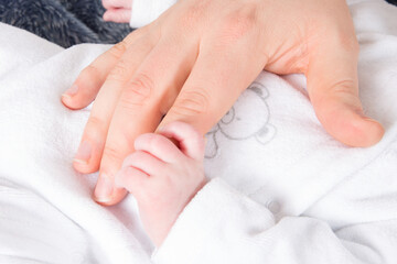 Fototapeta na wymiar Baby newborn little fingers grabs mother pather finger hand