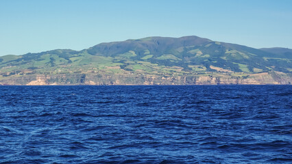 Fototapeta premium view from the swinging boat to the island, clear sunny weather, blue water