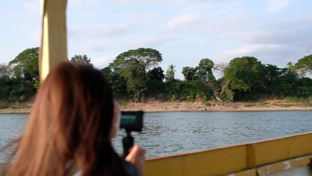 Slow motion of a female traveler taking photo with action camera while sailing long tail boat in the Mekong river