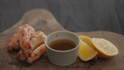 Slow motion gimbal shot of crab leg meat on a olive board with sweet lemon and dip sauce