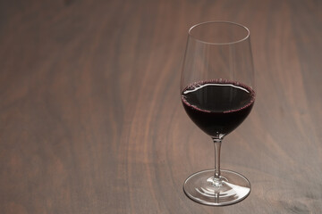 Red wine in wineglass on black walnut table with copy space
