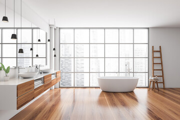 Bright bathroom interior with bathtub, oak wooden floor, panoramic window