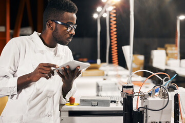 African engineer programming equipment with tablet at factory