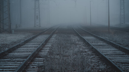 Several train rails ending in fog, railway tracks during a cold autumn morning