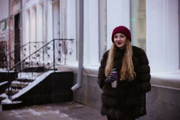 Fototapeta premium portrait of a white girl in winter in a fur coat who walks through the streets of the city