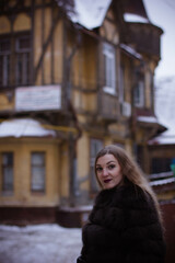 Naklejka premium portrait of a white girl in winter in a fur coat who walks through the streets of the city