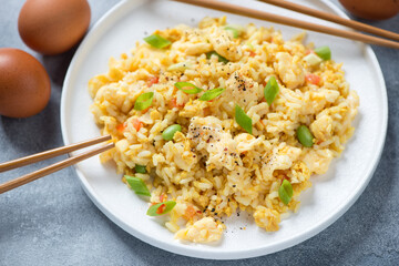 Chinese fried rice mixed with chicken eggs and served on a white plate, closeup, horizontal shot