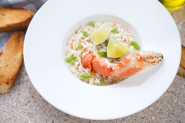 Crab risotto served with a boiled crab claw in a white plate, middle close-up, horizontal shot