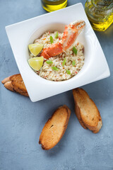 Plate of risotto with crab meat and baguette, high angle view on a grey concrete background, vertical shot