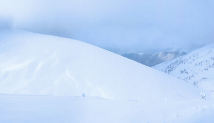 Winter mountain landscape. The cloud descends on a mountain range covered with snow. Panorama of several shots.