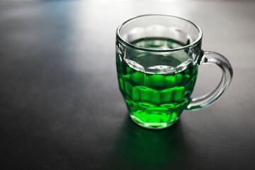 Saint Patrick's Day holiday. National Irish holiday. Green beer. Hand with a mug of emerald beer in a bar.