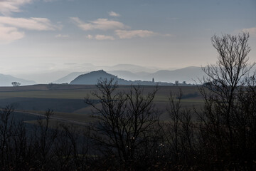 Paysage d'Auvergne avec des montagnes au loin baignées par de la brume le matin